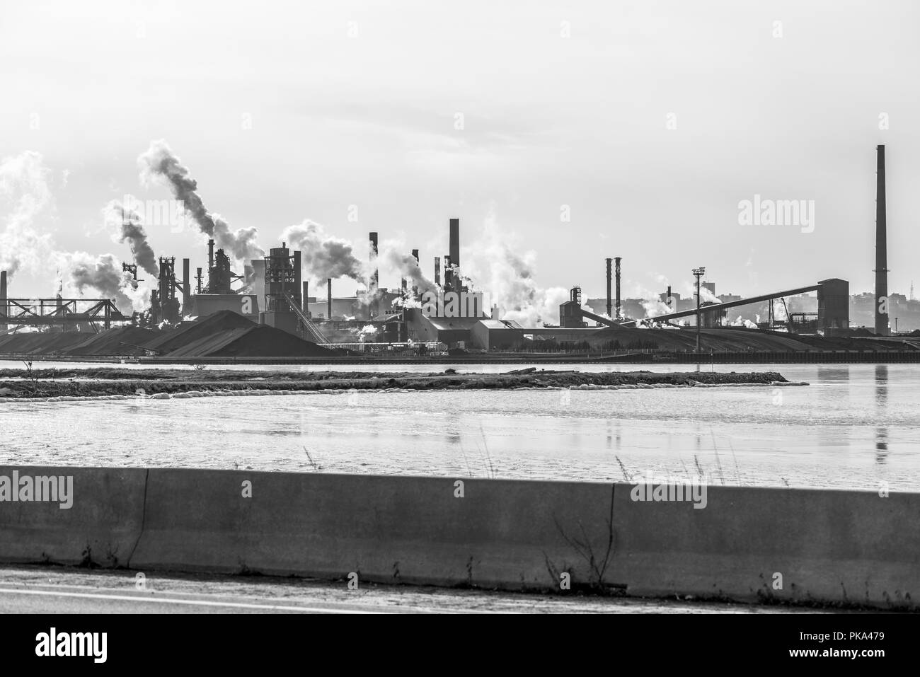 A black and white image of a steel mill spewing smoke into air in Hamilton Ontario Canada. Stock Photo