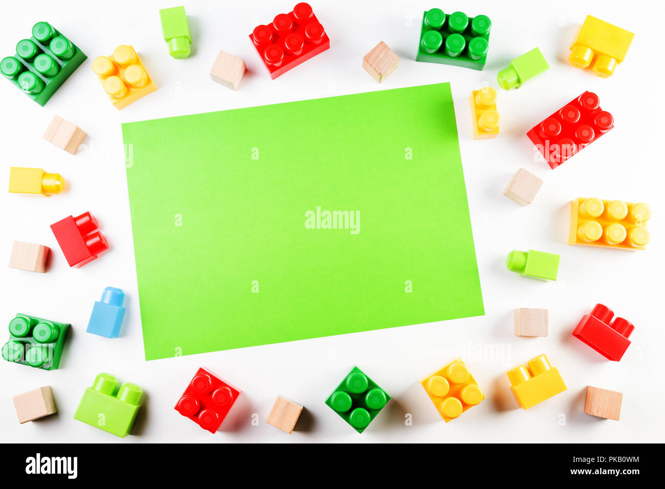 Colorful wooden cubes and plastic construction bricks with green blank
