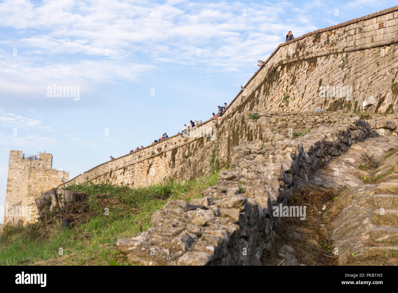 Outer wall of the Belgrade fortress Kalemegdan with tourists sitting along. Serbia. Stock Photo