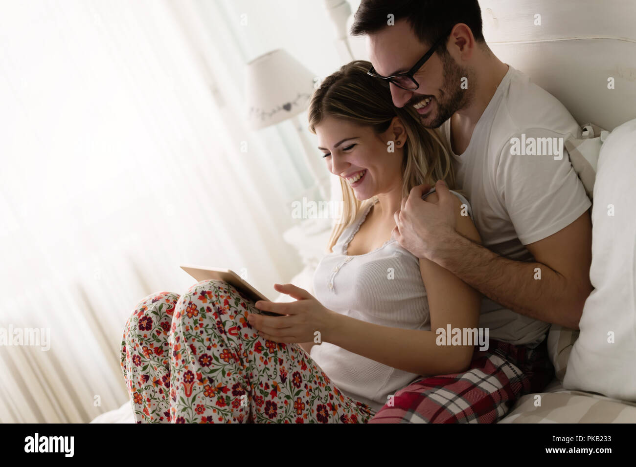 Young attractive couple using tablet in bedroom Stock Photo