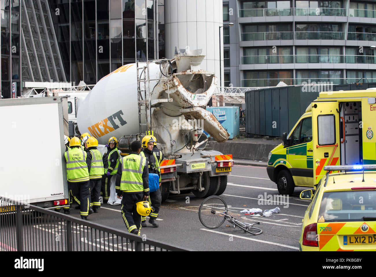 A paramedic looks down at the remains of a cyclists damaged bycycle after colliding with a concrete lorry on Old Street roundabout, London, UK Stock Photo