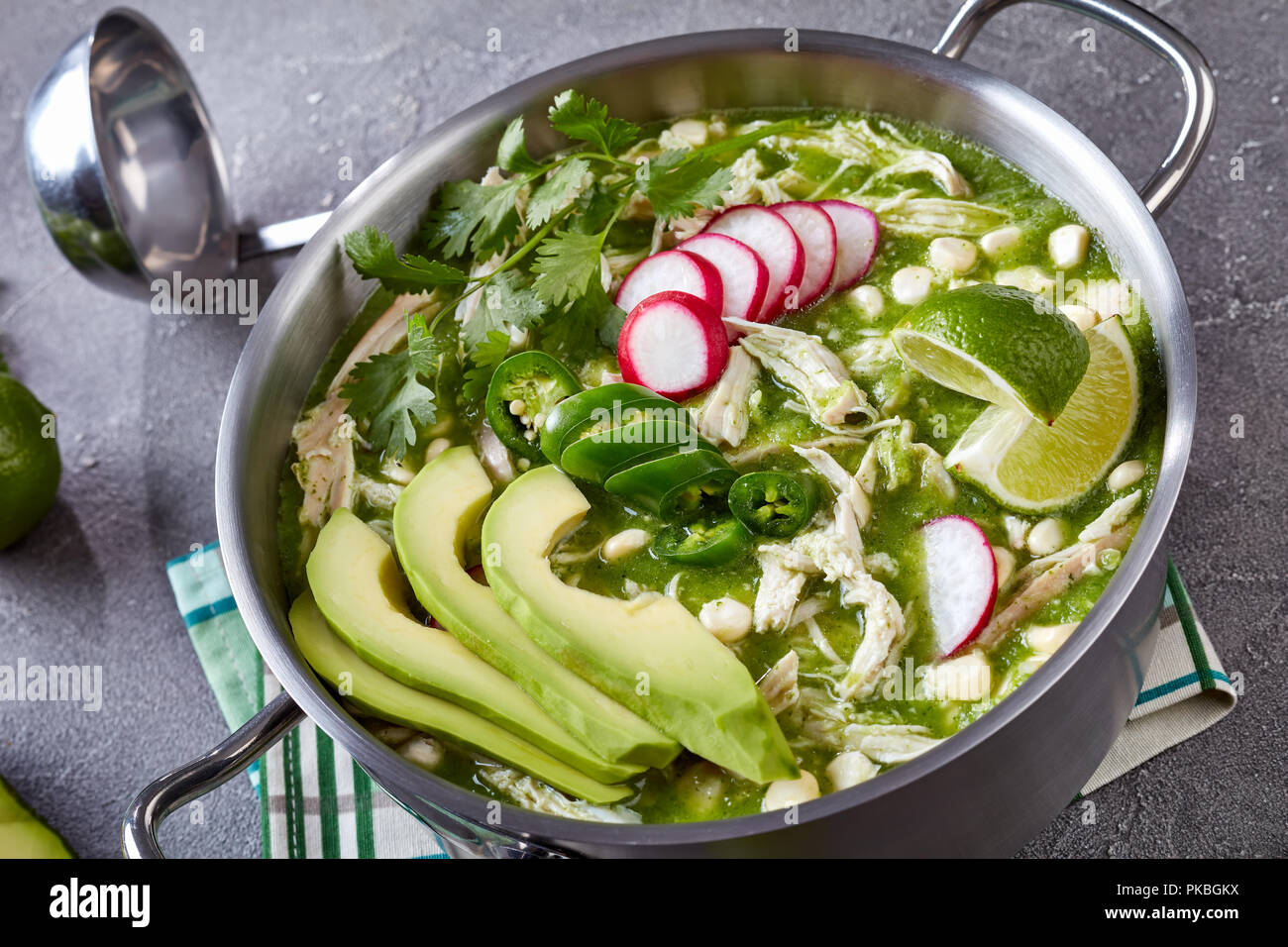 Chicken Pozole Verde in a pot - Mexican stew filled with shredded chicken and hominy in a warm green chile broth garnished with radish slices, cilantr Stock Photo