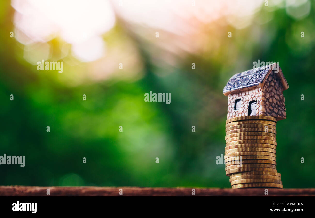 Coin money and house model on on green nature background. Concept for investment, saving, finance, banking, property ladder, mortgage and real estate  Stock Photo