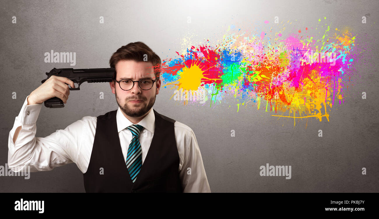 Man shoots his head with gun and colorful splotch are coming out from his head Stock Photo