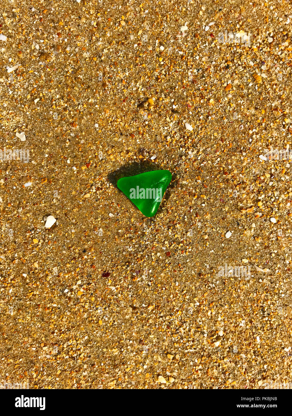 Green triangle glass on the yellow sand, summer, morning Stock Photo