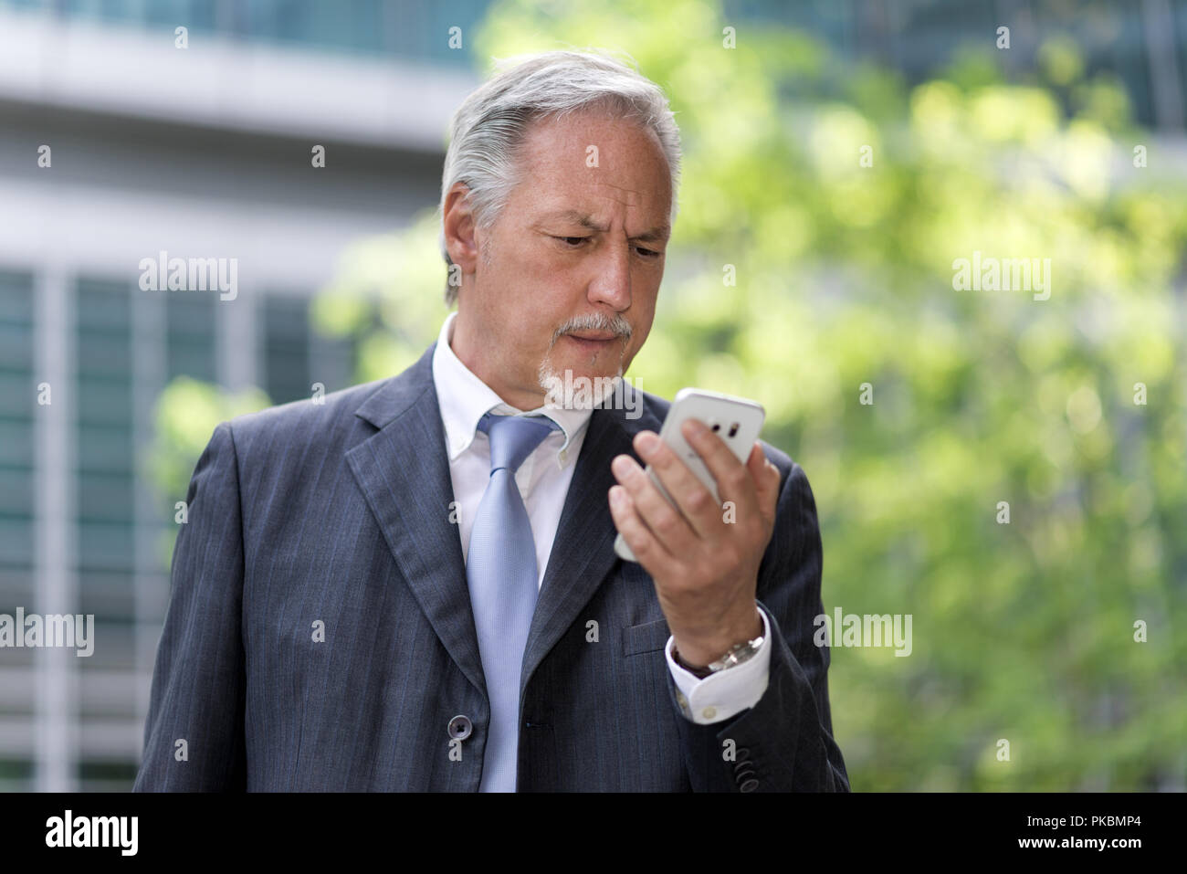 Pensive businessman looking at his cellphone Stock Photo