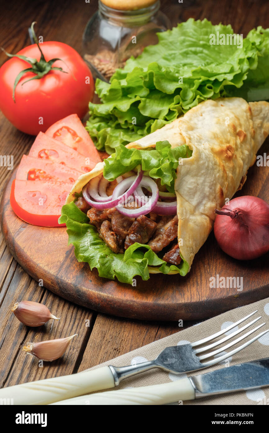 Doner kebab is lying on the cutting board. Shawarma with meat, onions ...