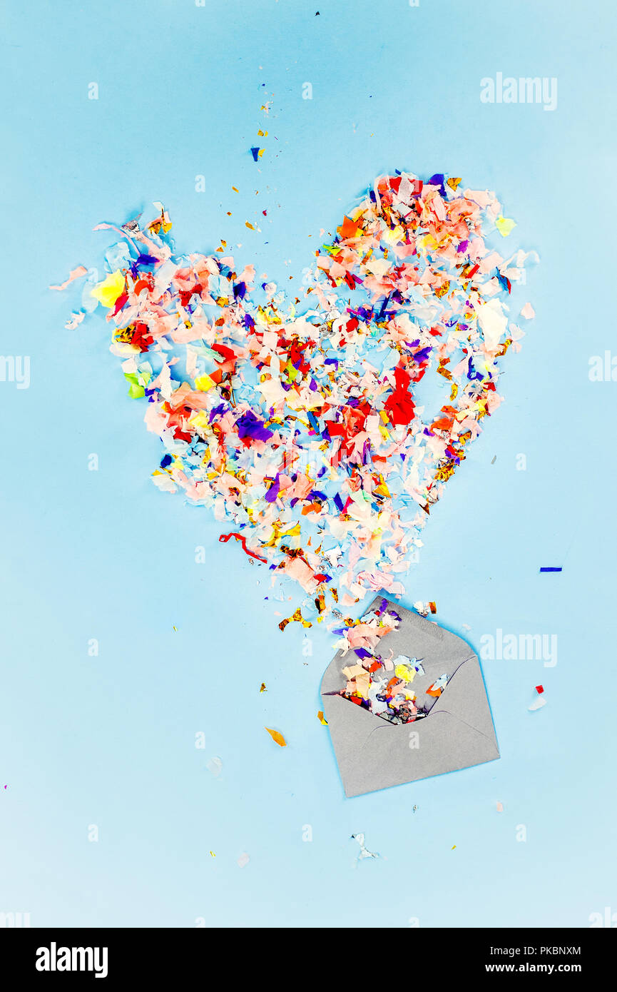 Envelope with party confetti explosion on pastel blue background Stock