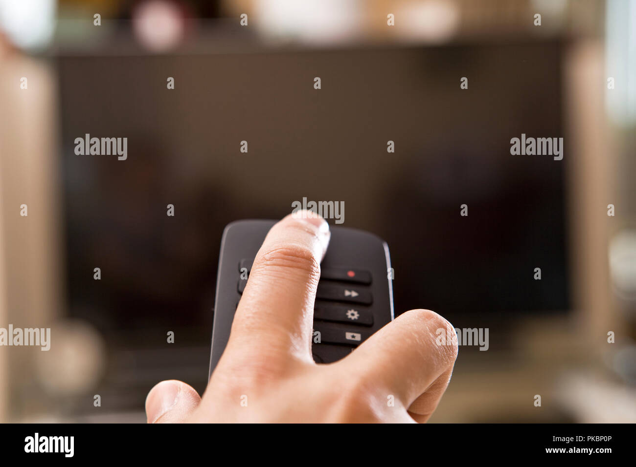 Yong man hand with remote changes channels Stock Photo