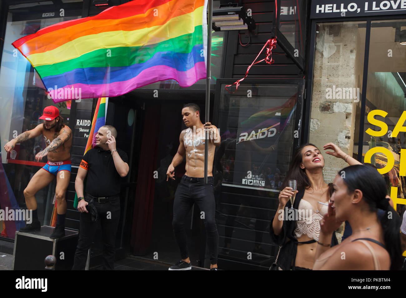 Shirtless muscular go-go dancer performs with a rainbow flag during a  street party outside the Raidd Bar in occasion the Paris Gay Pride (Marche  des Fiertés) in Paris, France, on 30 June