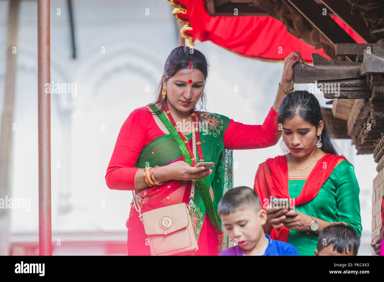 Kathmandu,Nepal - Sep 12,2018:Nepali Hindu Women using mobiles at Kathmandu Durbar Square in Kathmandu. Hindu Nepali Women fast and wish for a prosperous life of their spouse and family on this festival.The festivals for women, include dancing, singing, getting together with friends,, wearing red, green or orange clothes, sharing festive foods Credit: Nabaraj Regmi/Alamy Live News Stock Photo