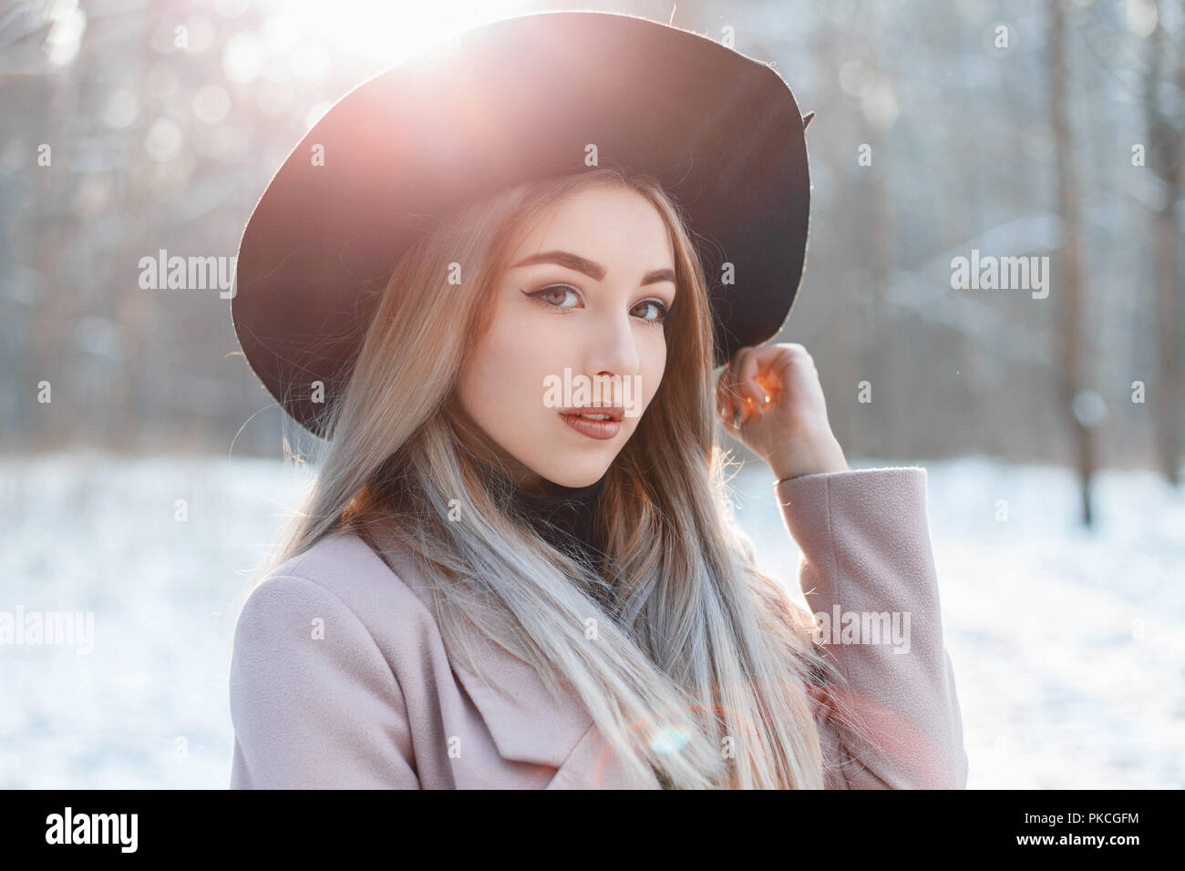 Portrait of a young beautiful girl in a black hat on a winter day at ...