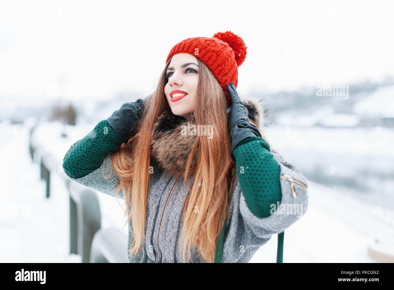 Happy beautiful girl smiling and looking up in stylish winter clothes on a  background of a snowy landscape Stock Photo - Alamy