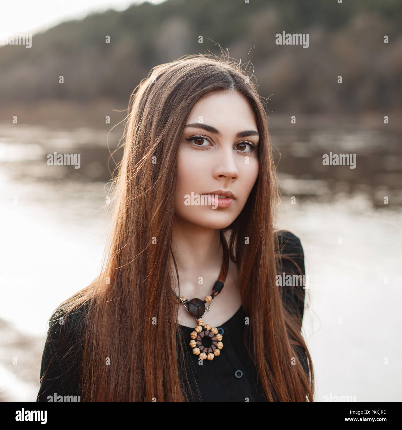 Beautiful portrait of a young pretty girl with long hair near the water ...