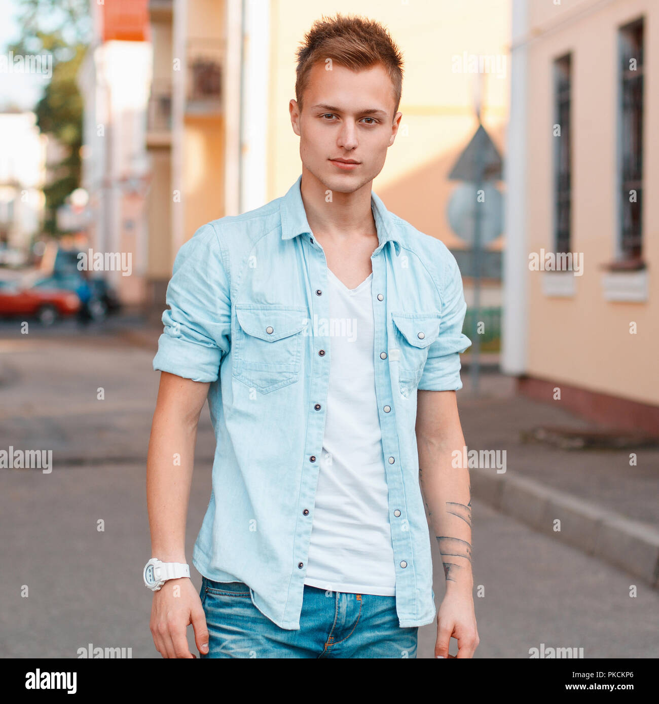 Young handsome man in a denim shirt and jeans on the background of the city. Stock Photo