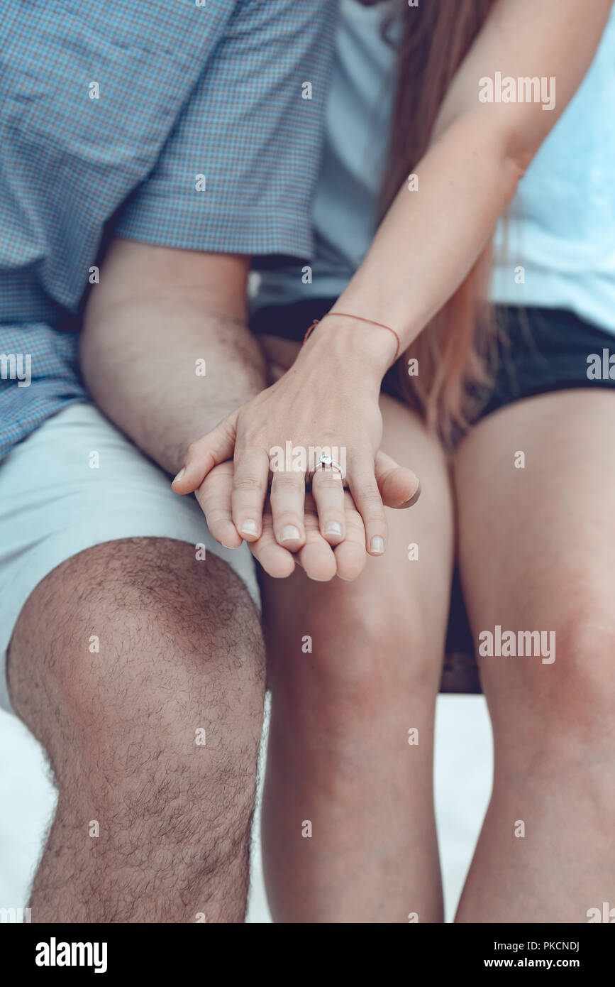 Engagement at the beach of tropical island. Close up of couple hands with silver ring on the finger. Stock Photo