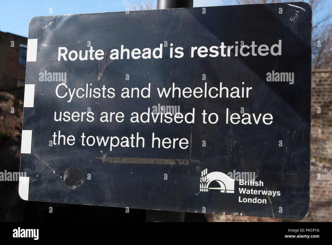 british waterways sign on the grand union canal stating route ahead is restricted and that cyclists and wheelchair users should leave the towpath Stock Photo