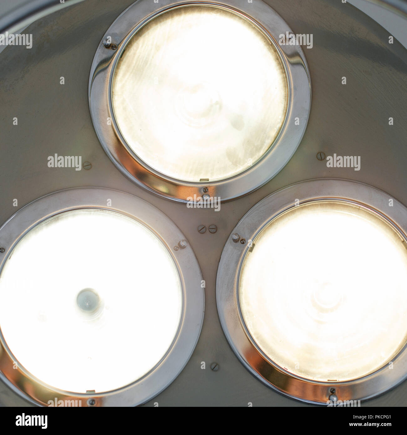 Bright light shines in the operating room. Metal surgical lamp. Stock Photo