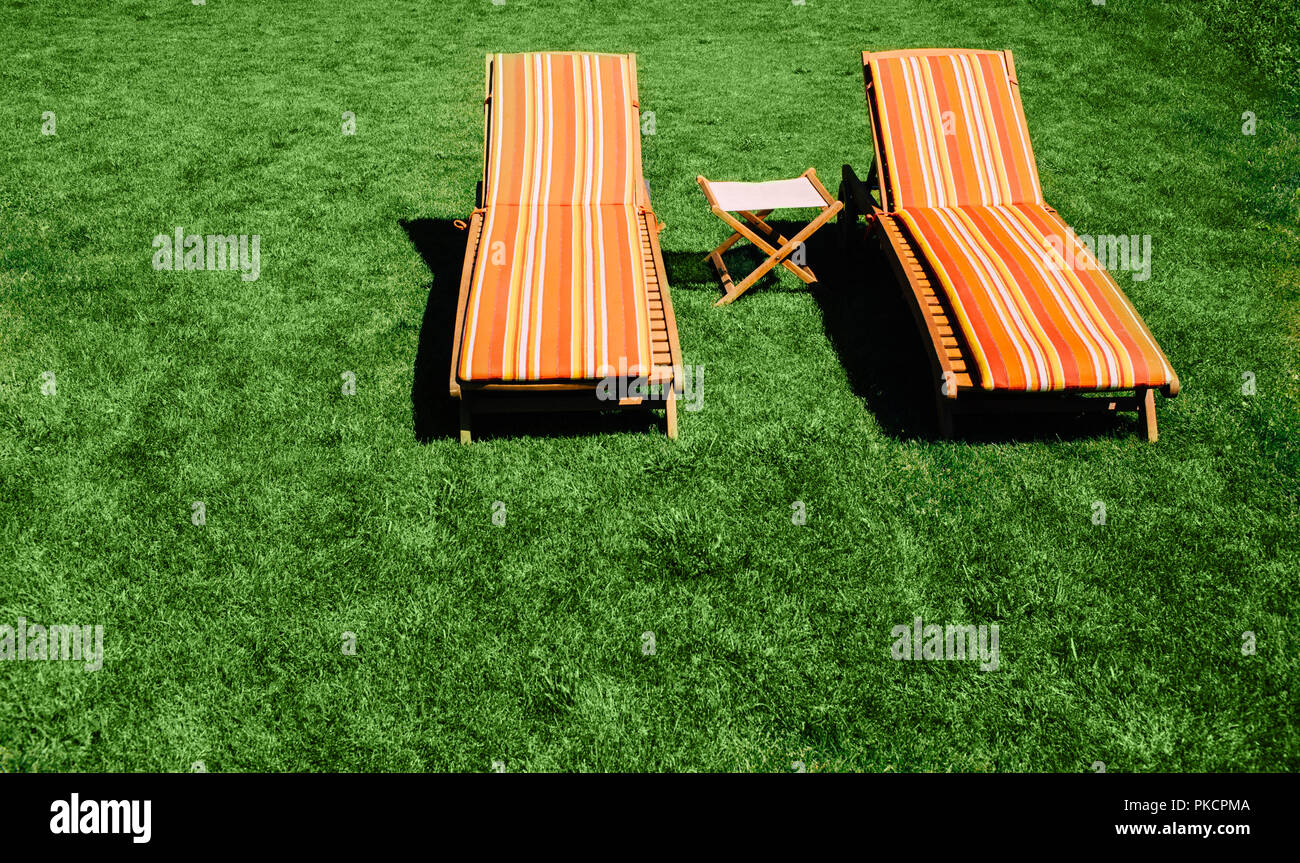Two Chaise Longue on the green grass, top view, summer vacation Stock Photo