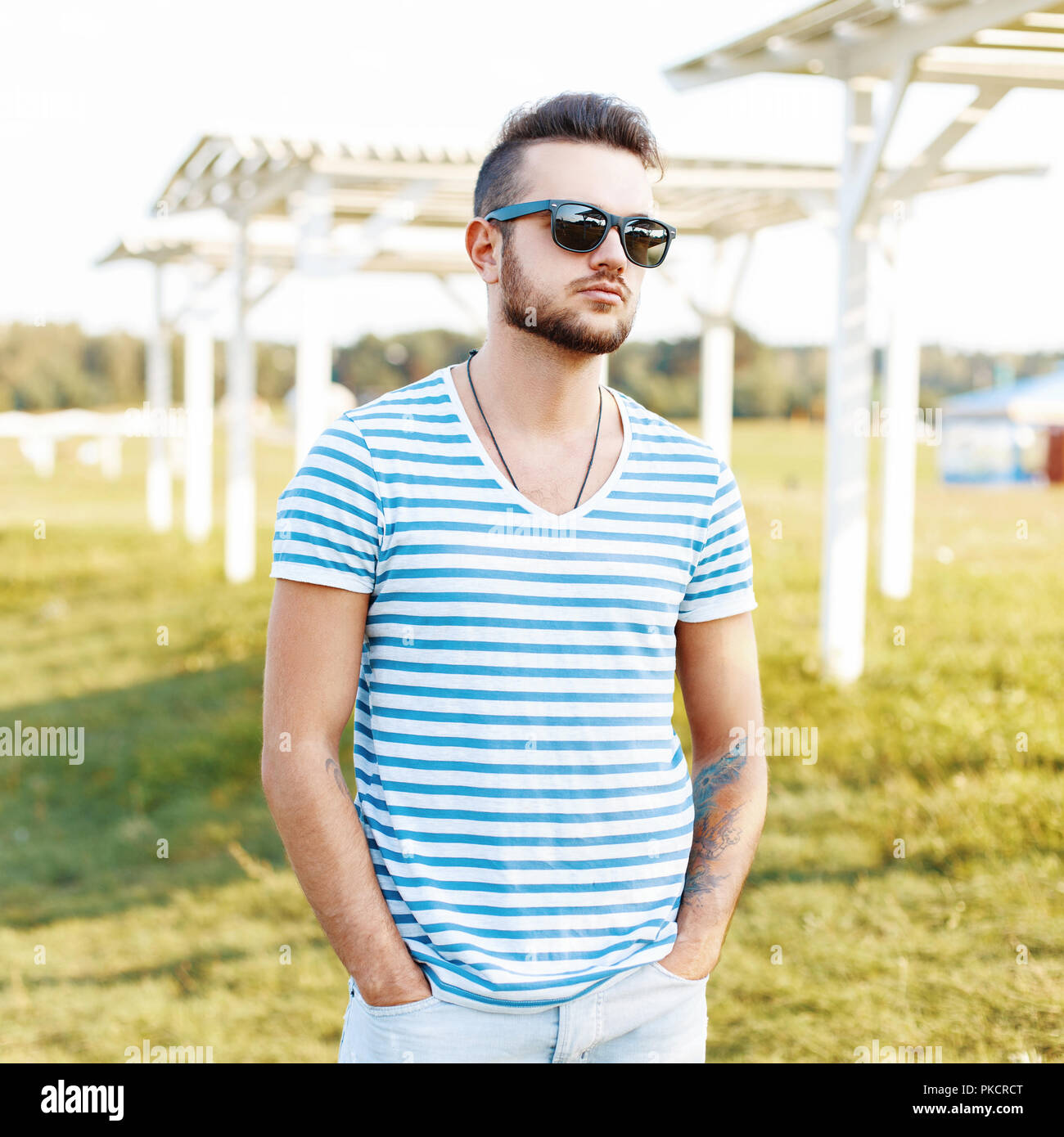 Handsome man in a stylish shirt and sunglasses resting on the beach. Stock Photo