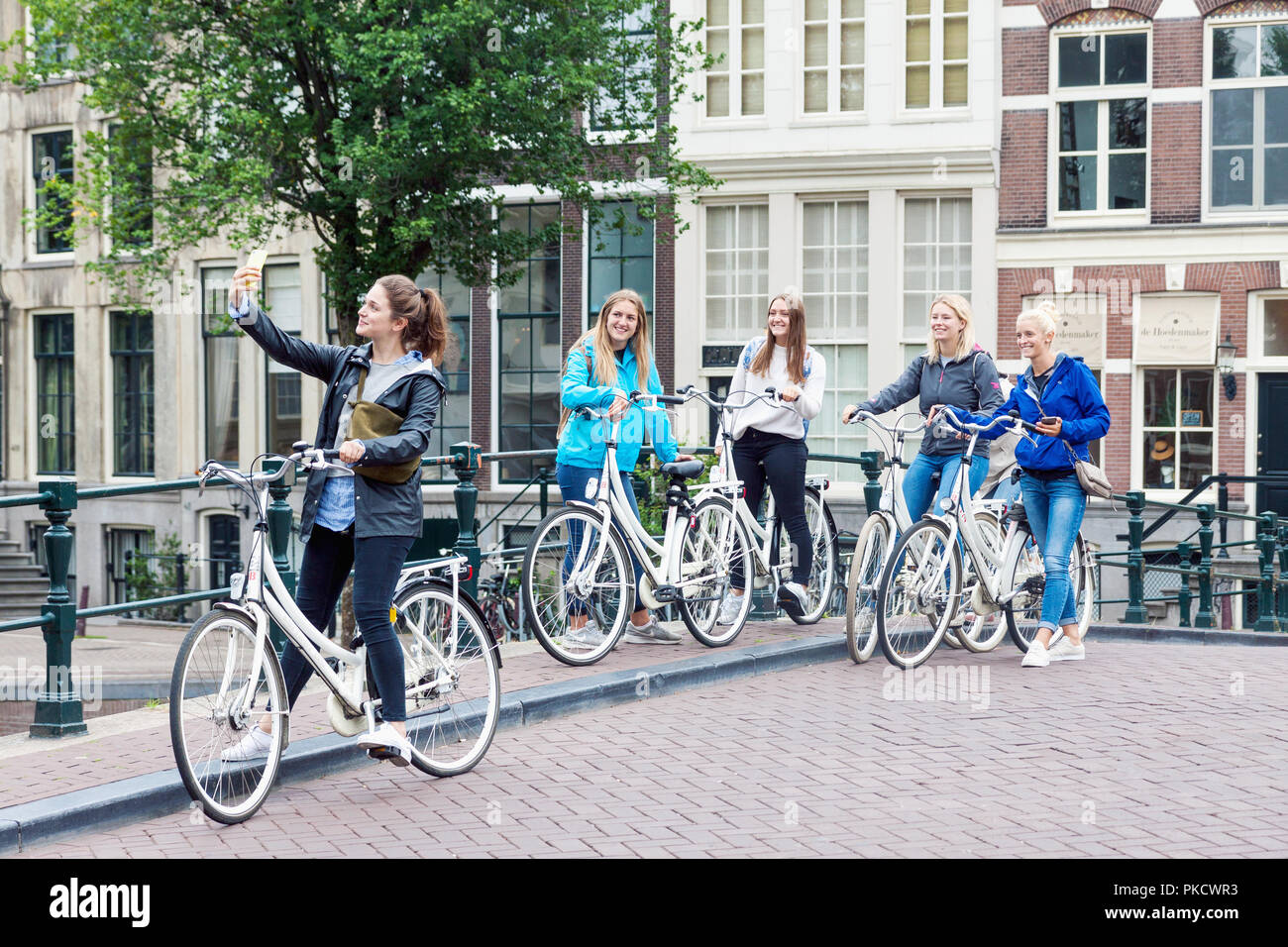 Group of happy smiling young female girls with rented bicycles taking selfie photo on the street in Amsterdam Stock Photo