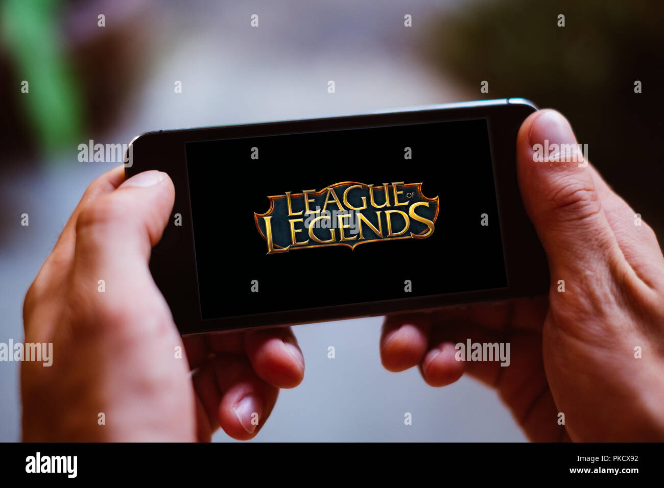 Closeup of hands holding smartphone screen with LEAGUE OF LEGENDS GAME LOGO and ICON Stock Photo