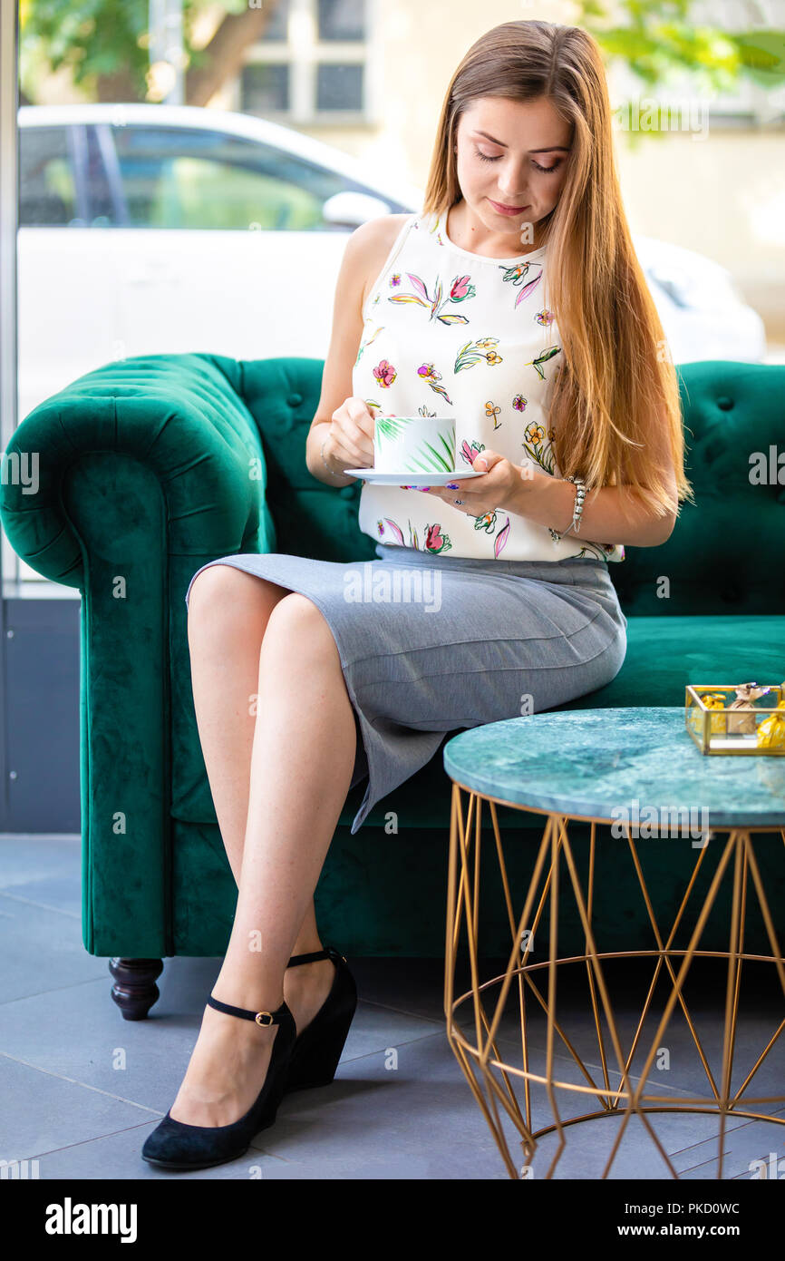 Young woman sitting on sofa drinking tea from cup in a office Stock ...