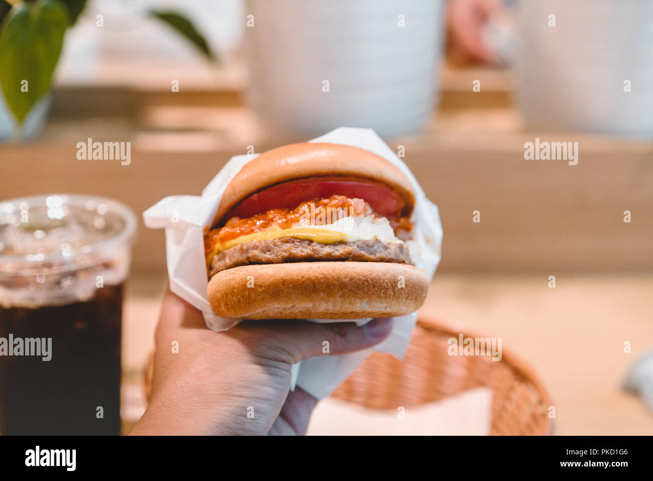 Hands holding fresh delicious burgers with coffee. Stock Photo