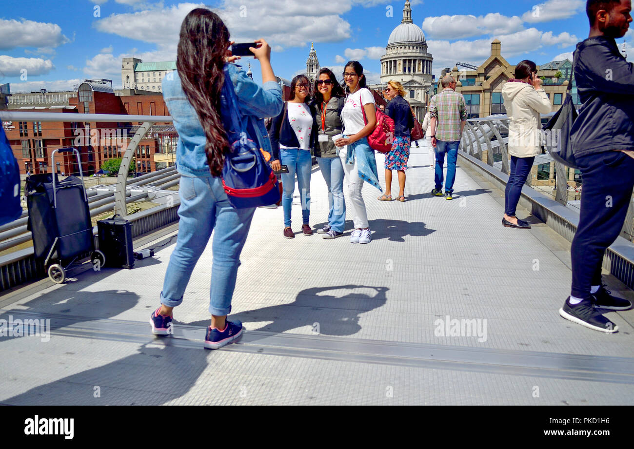 Friends posing on the Millennium Bridge for a photo in front of St Paul's Cathedral. London, England, UK. Stock Photo