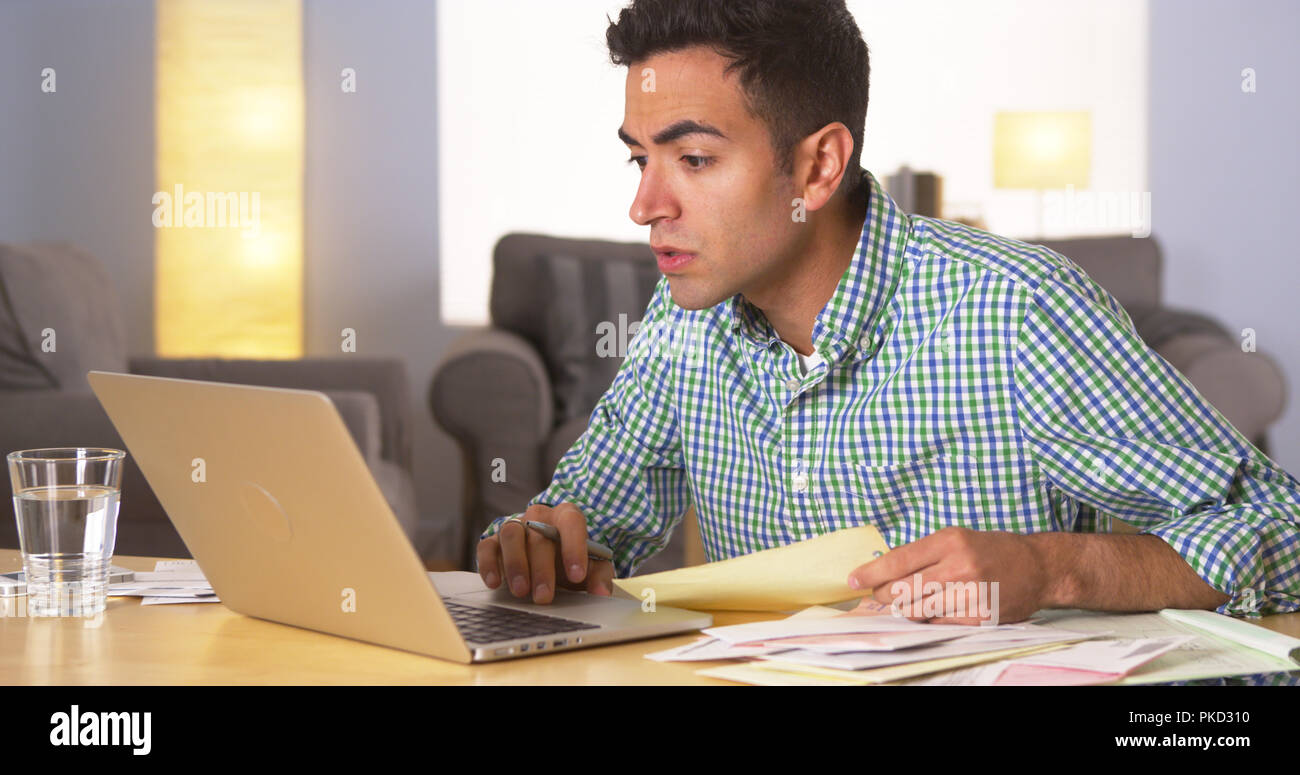 Hispanic man paying bills at home Stock Photo