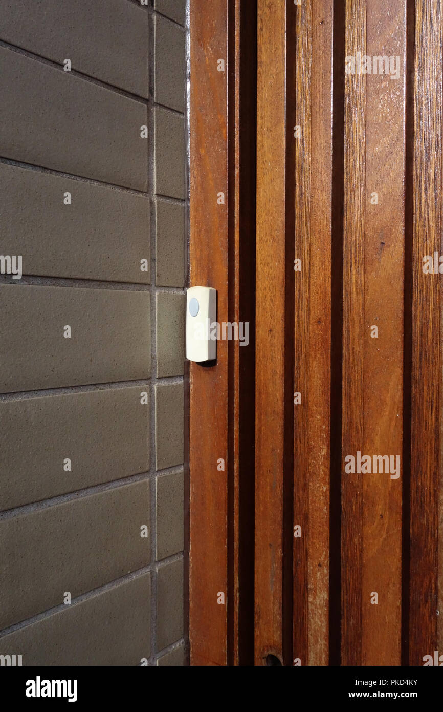 Plastic doorbell on strong wooden door Stock Photo