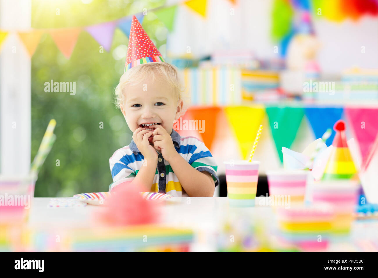 Kids birthday party. Child blowing out candles on colorful cake ...