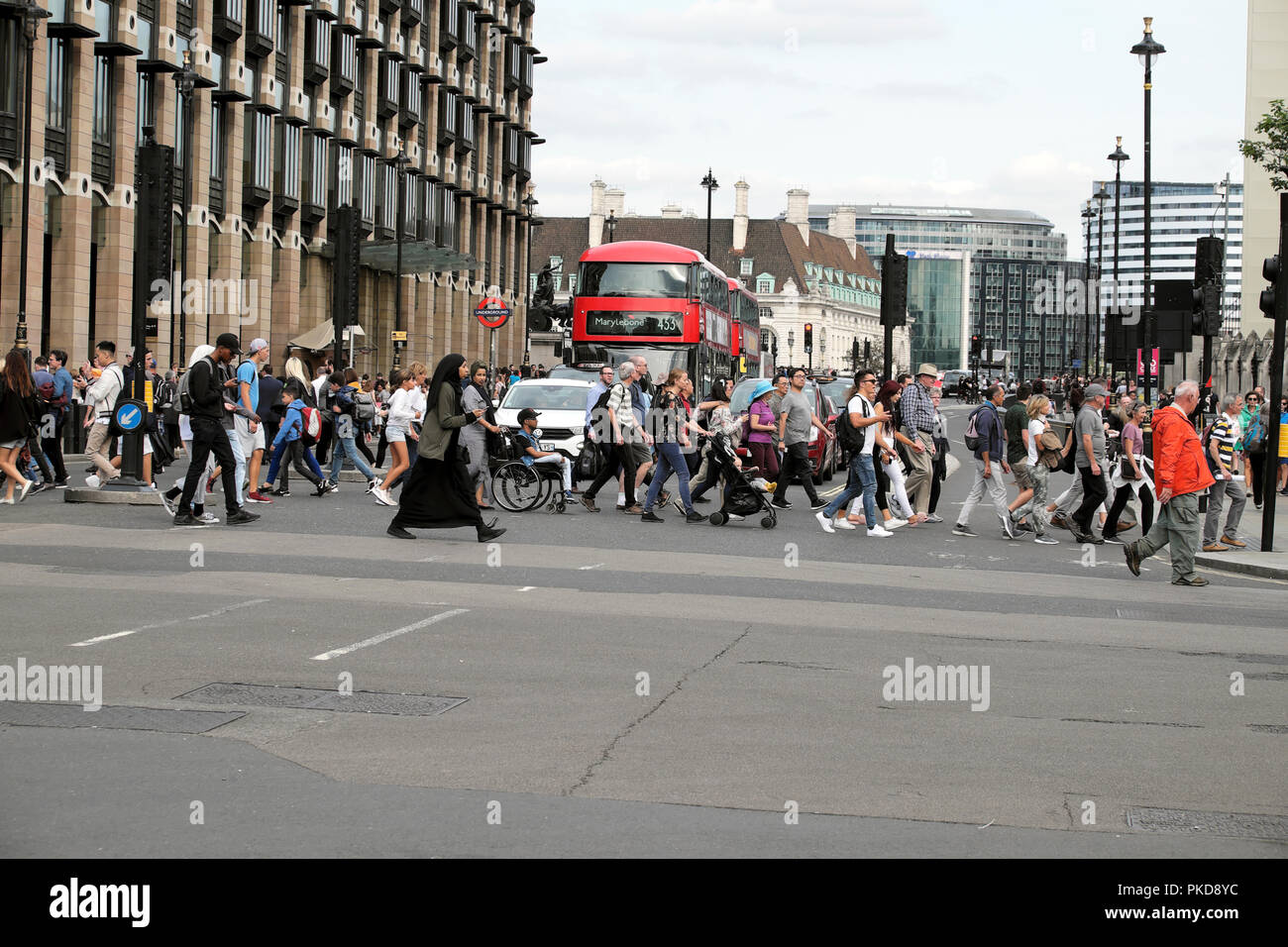 Pedestrians and tourists cross the road at Bridge Street traffic lights pedestrian crossing outside the Houses of Parliament Westminster London UK Stock Photo