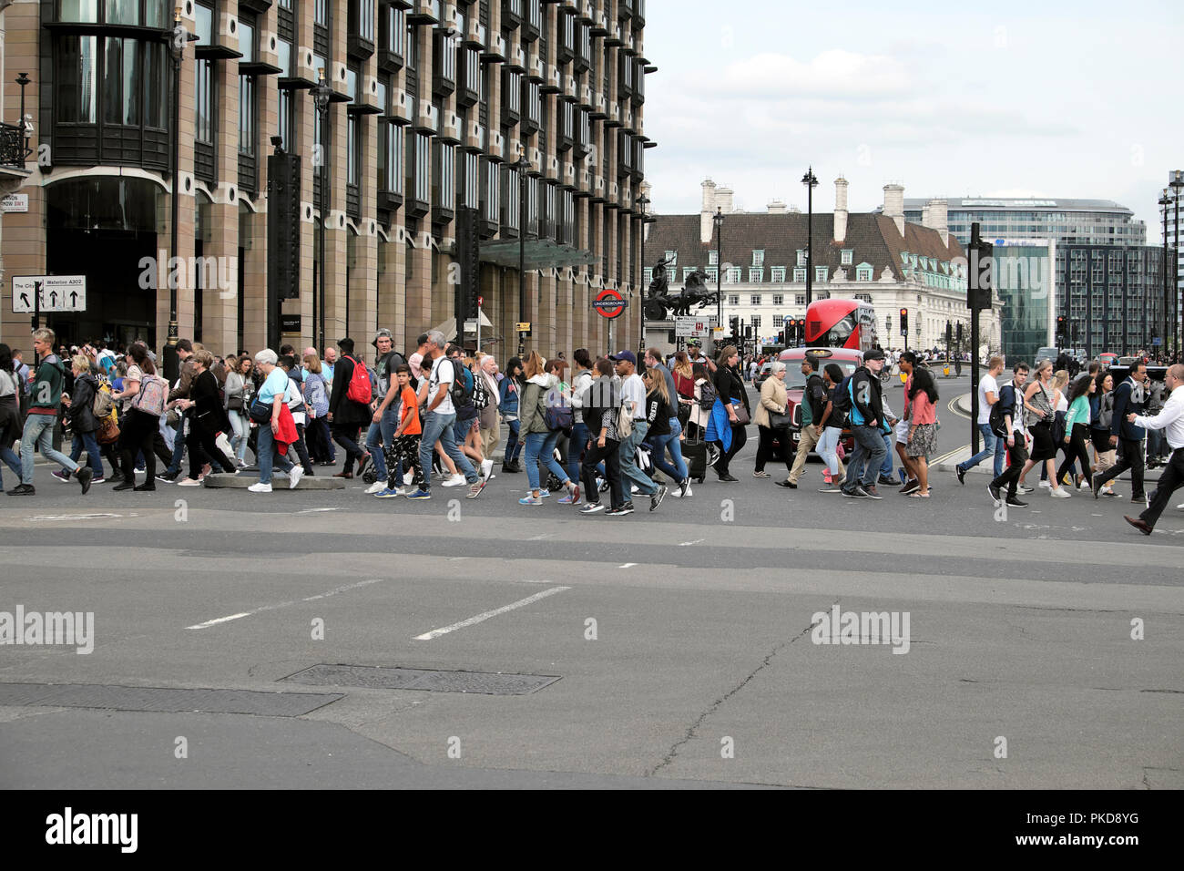 Pedestrians and tourists cross the road at Bridge Street traffic lights pedestrian crossing outside the Houses of Parliament Westminster London UK Stock Photo