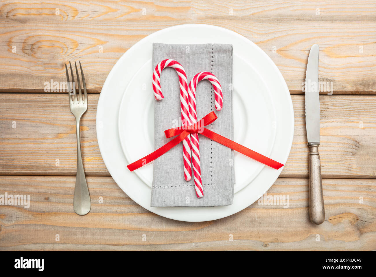 Christmas table setting. Candy canes on white plates and cutlery ...