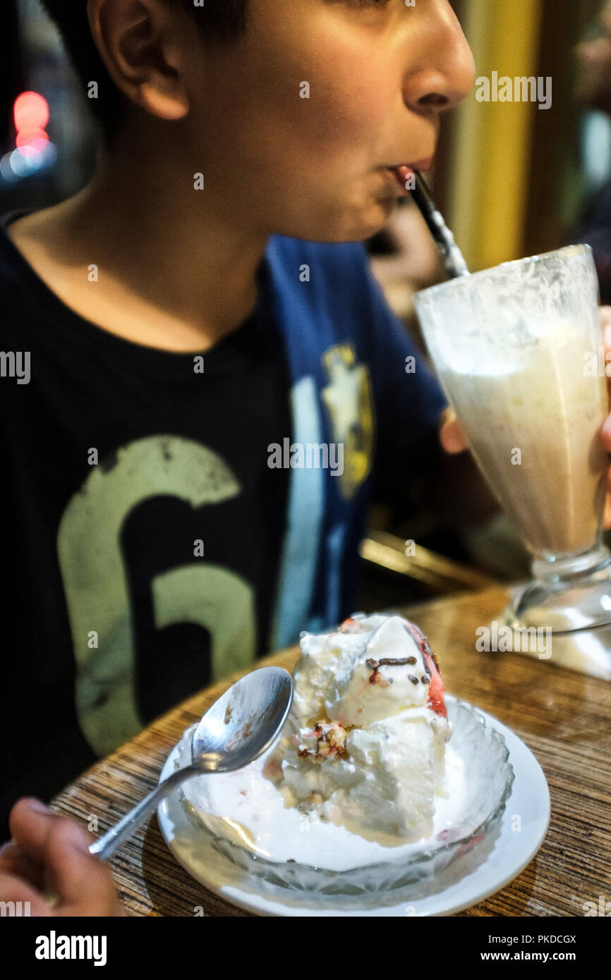 Sugar addiction- child eats ice cream and drinks milk shake Stock Photo