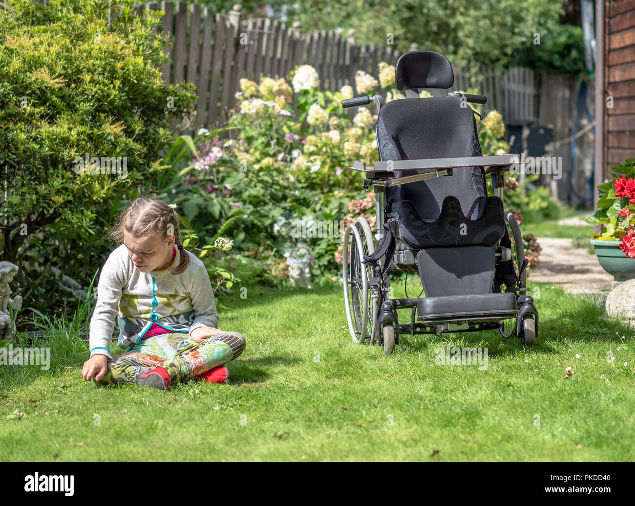 A disabled child having a break from sitting in her wheelchair to explore her natural surroundings Stock Photo