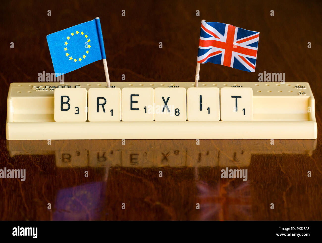 Scrabble letters spelling Brexit in Scrabble tray with British Union Jack and EU flags on dark mahogany background Stock Photo