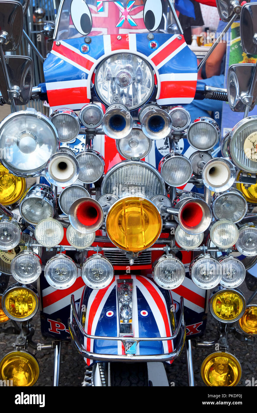 front view of a moped scooter that is painted in British union jack flag colors there are 20 head lights and four horns on the front of the moped Stock Photo