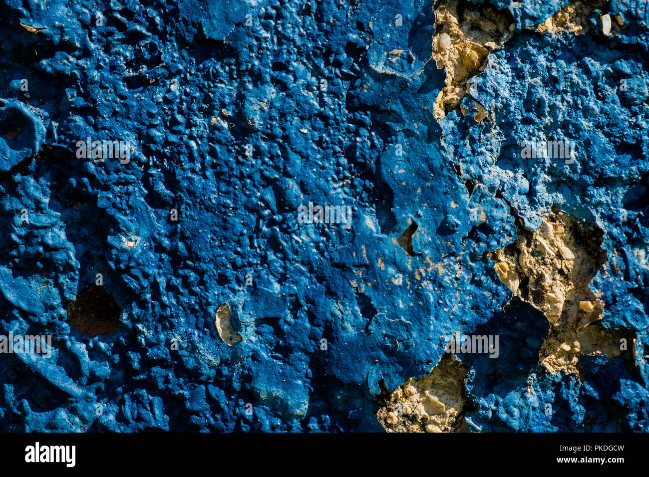 Yellow stone wall with dark blue plaster pealing off/grunge wall texture background Stock Photo
