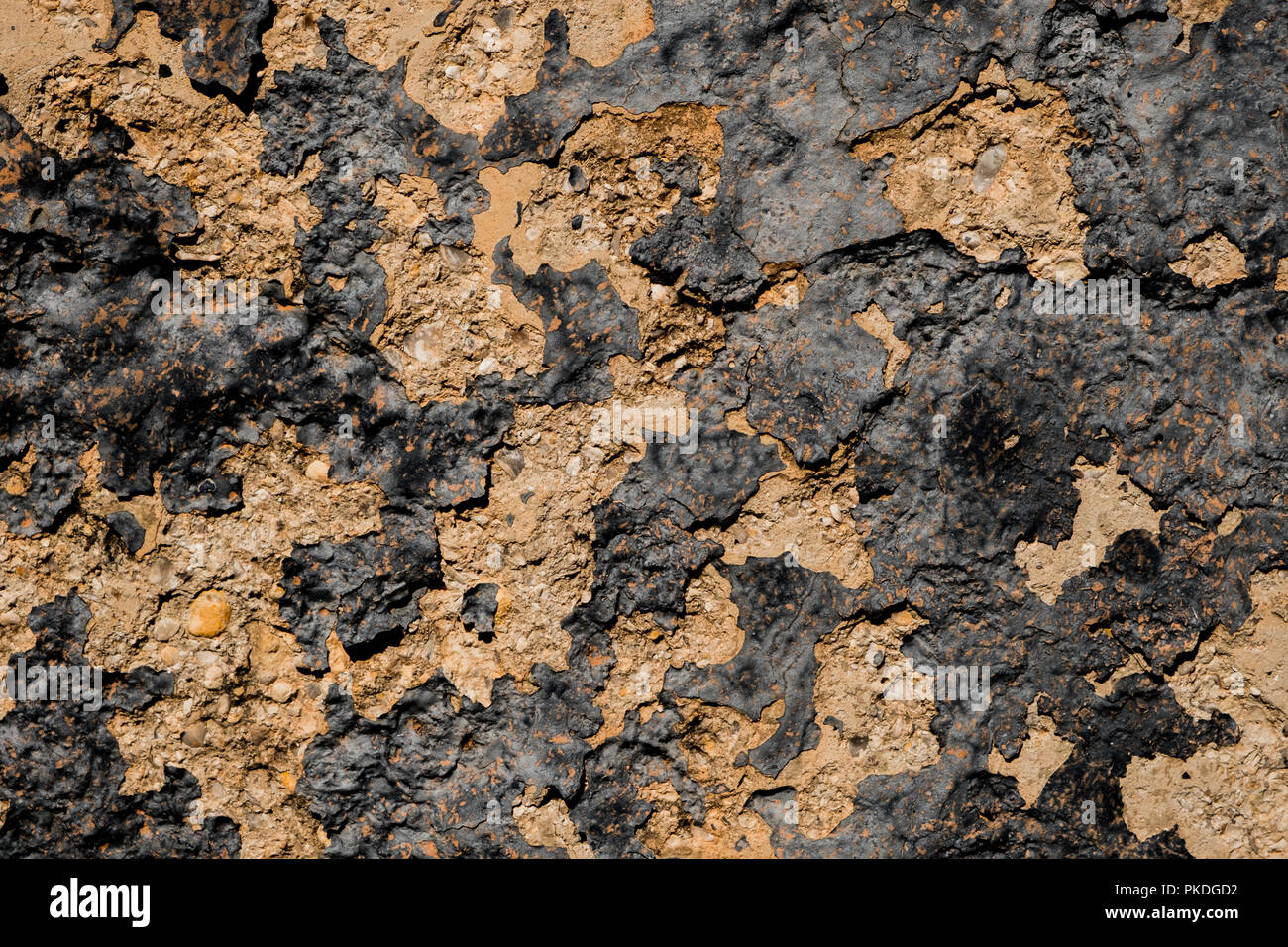 Yellow stone wall with dark paint pealing off/grunge wall texture background Stock Photo