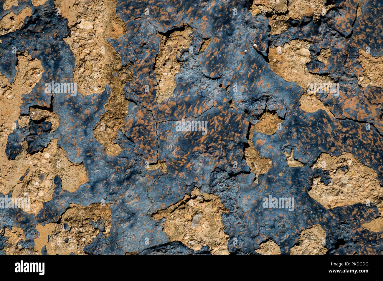 Yellow stone wall with dark blue paint pealing off/grunge wall texture background Stock Photo