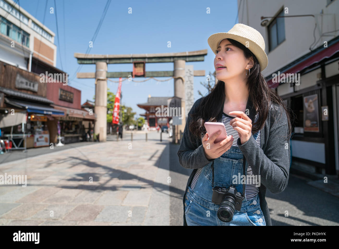 brilliant female traveler using a phone and searching the places in the shopping street of osaka. Stock Photo
