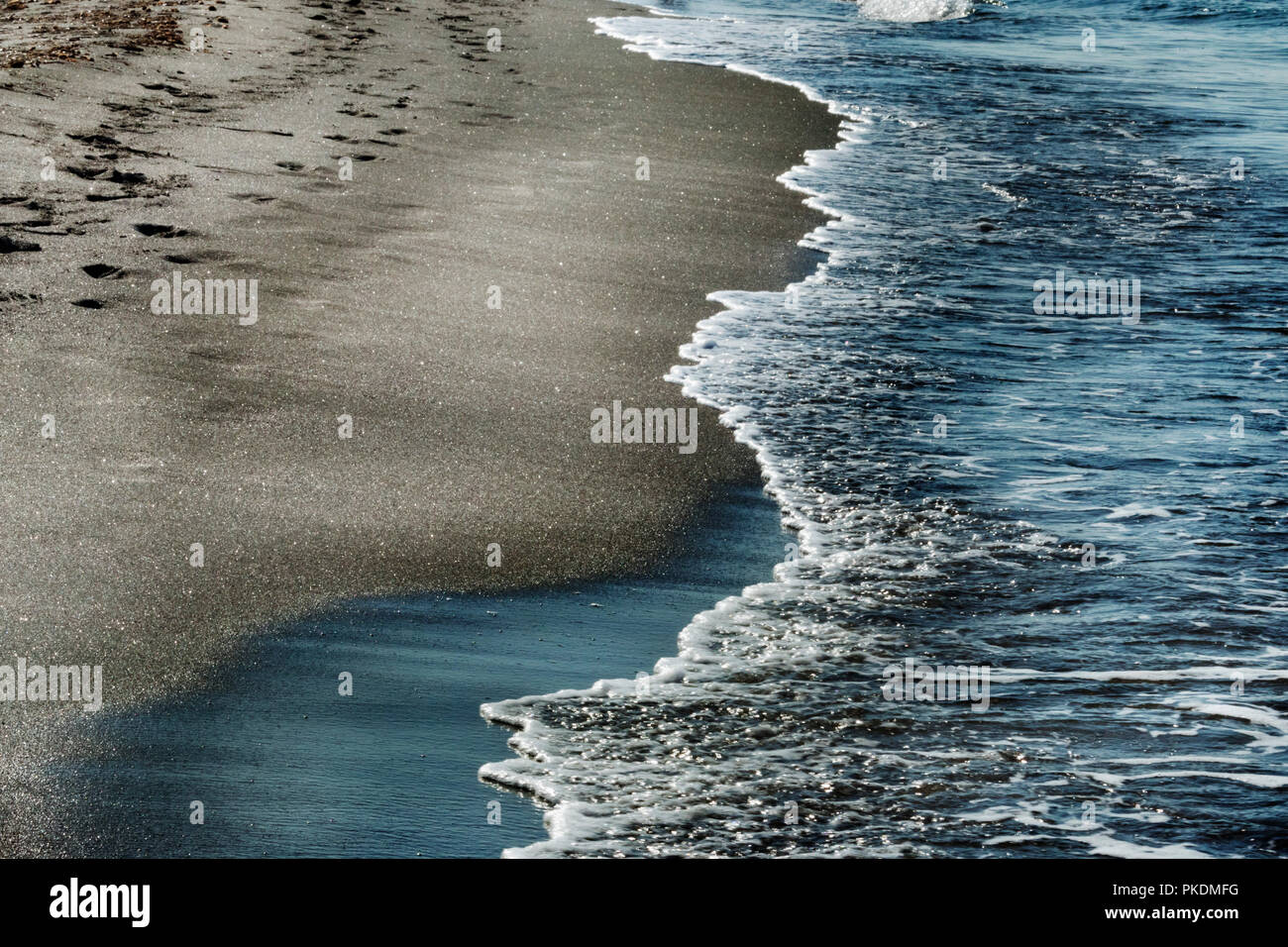 Down to the edge of the sea , footmarks on the beach ,blue water and bright  foam of the sea , saturated colors ,melancholy and romanticism Stock Photo  - Alamy