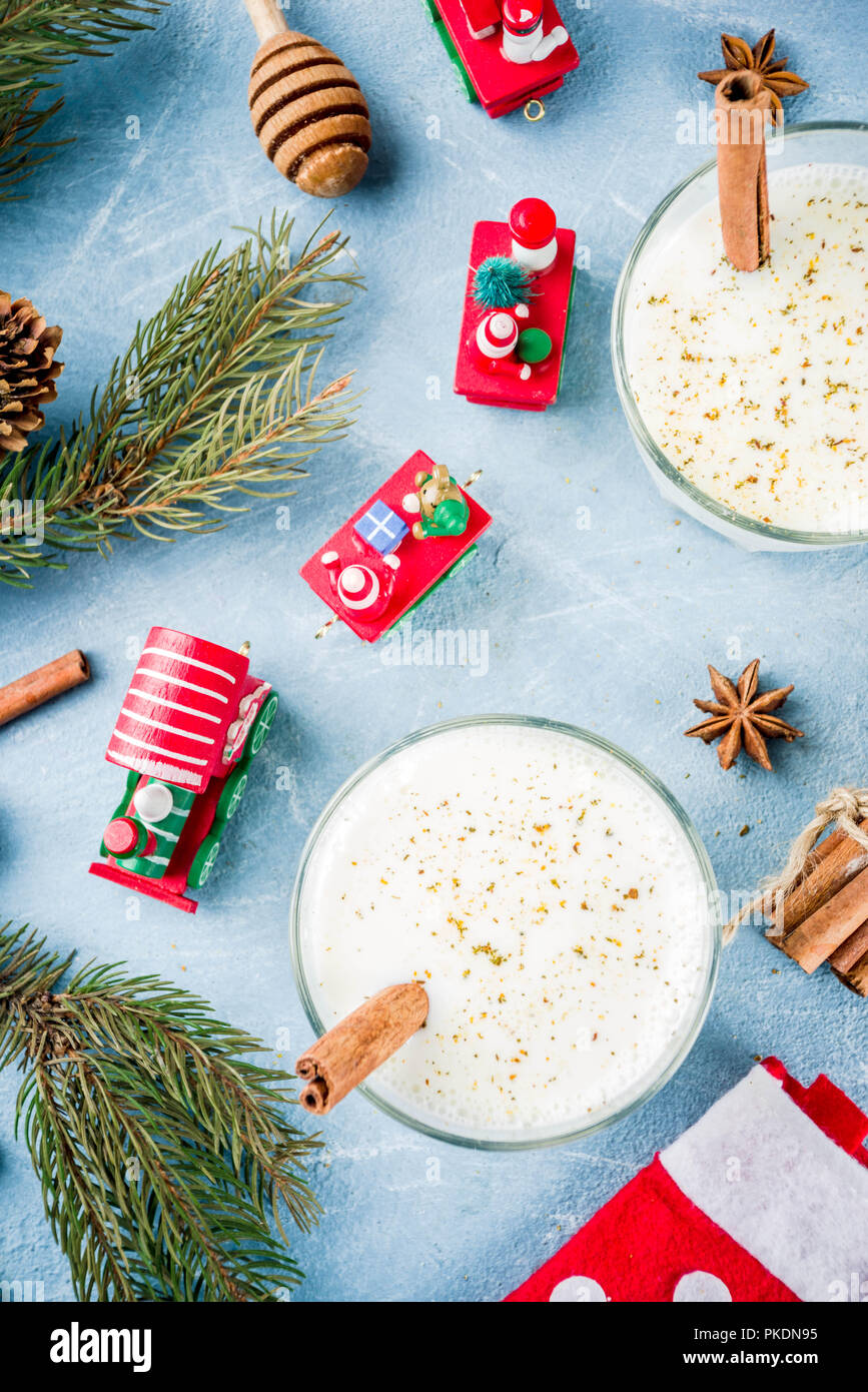 Traditional winter festive drink, sweet and spicy christmas eggnog cocktail in a glasses, on light blue background with xmas decorations, copy space. Stock Photo