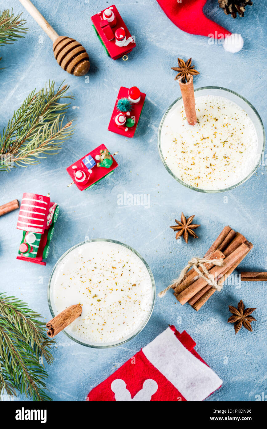 Traditional winter festive drink, sweet and spicy christmas eggnog cocktail in a glasses, on light blue background with xmas decorations, copy space. Stock Photo