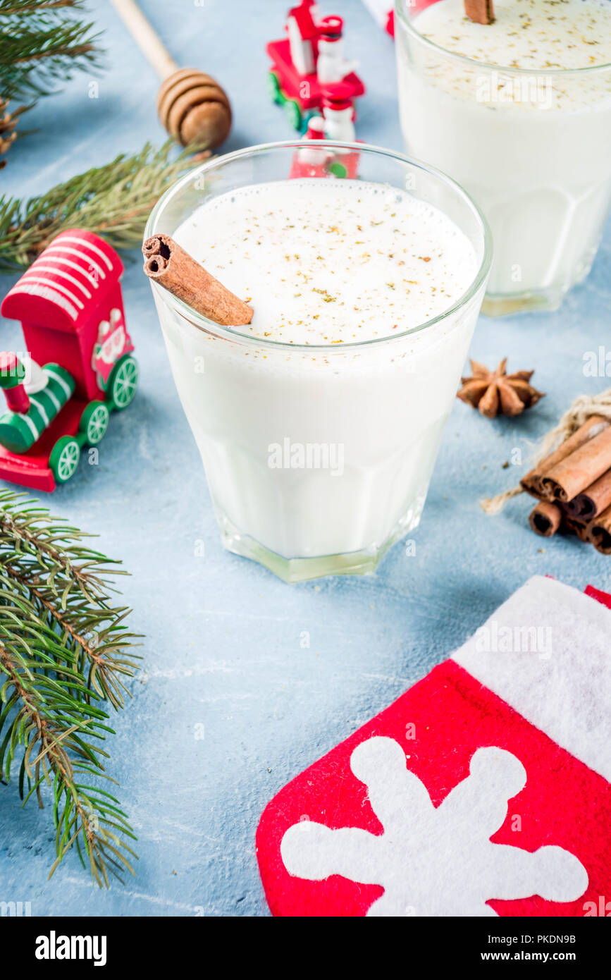 Traditional winter festive drink, sweet and spicy christmas eggnog cocktail in a glasses, on light blue background with xmas decorations, copy space. Stock Photo