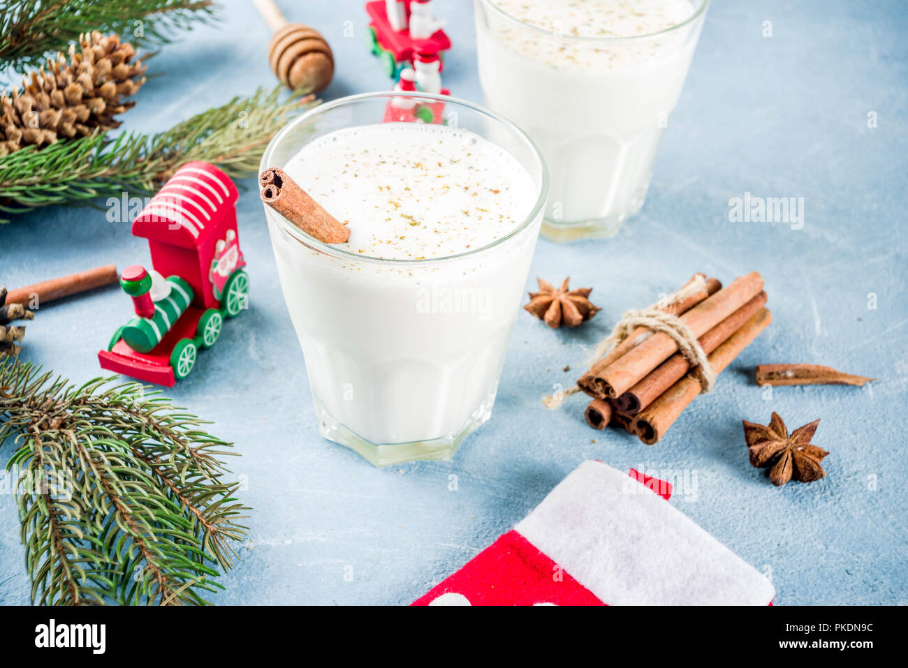 Traditional winter festive drink, sweet and spicy christmas eggnog cocktail in a glasses, on light blue background with xmas decorations, copy space. Stock Photo