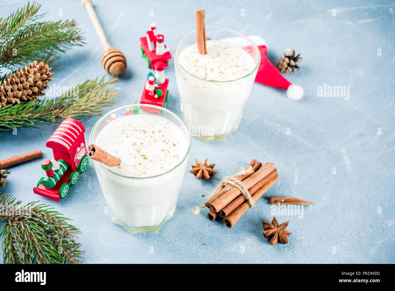 Traditional winter festive drink, sweet and spicy christmas eggnog cocktail in a glasses, on light blue background with xmas decorations, copy space. Stock Photo