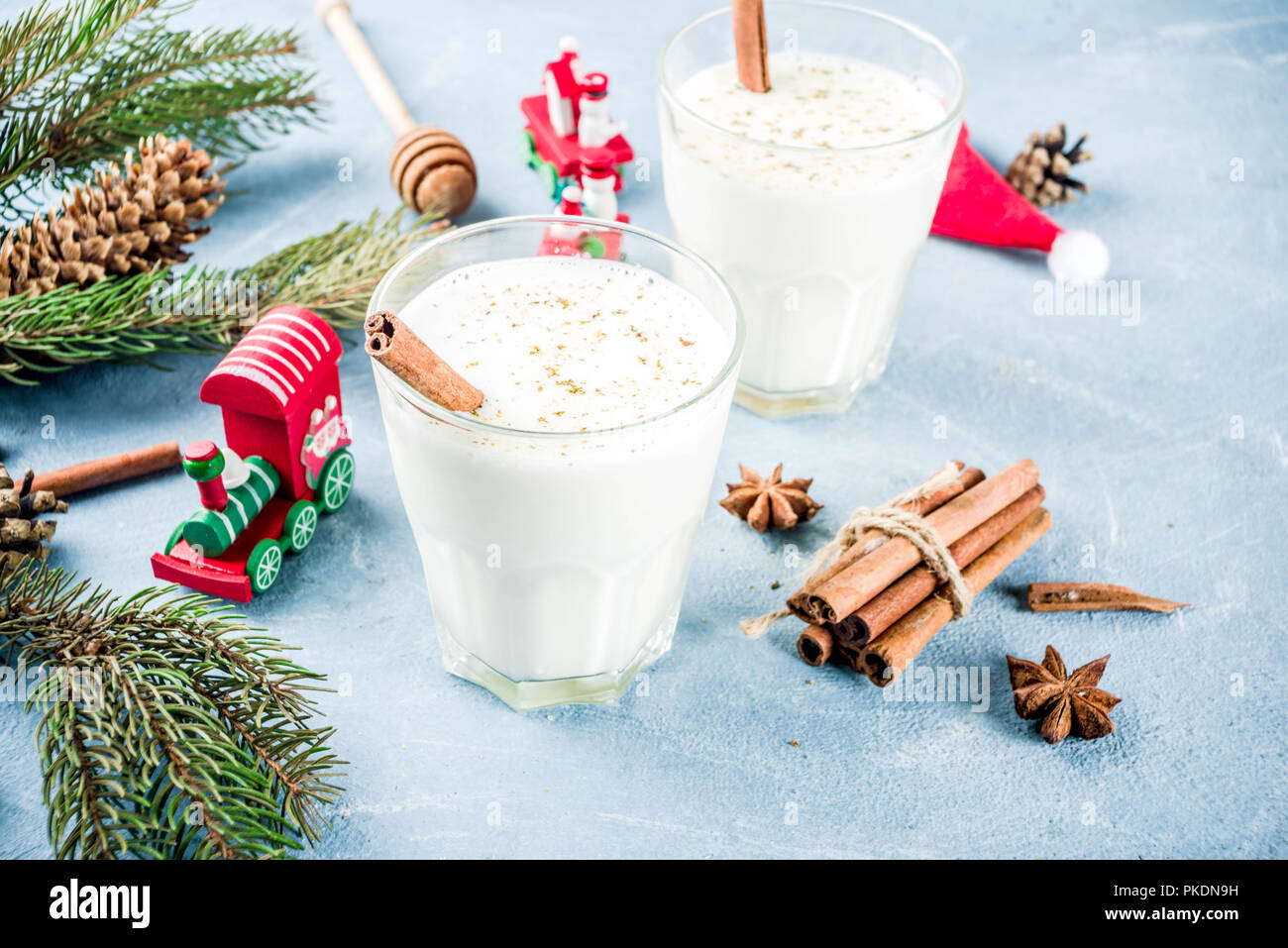 Traditional winter festive drink, sweet and spicy christmas eggnog cocktail in a glasses, on light blue background with xmas decorations, copy space. Stock Photo